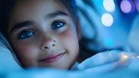 Young girl with blue eyes lying in bed at night with colorful bokeh lights creating dreamy atmosphere for children sleep and bedtime concepts.