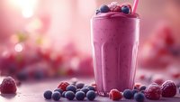 Berry smoothie with fresh blueberries and raspberries in tall glass on wooden table. Healthy breakfast drink with antioxidants for nutrition and wellness lifestyle.