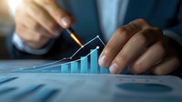 Asian businessman analyzing financial growth chart with pencil on desk, blue tinted corporate data report showing increasing market trend and success.