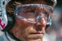 Close-up portrait of mature Caucasian male athlete wearing protective helmet and goggles, showcasing determination during extreme sports competition.