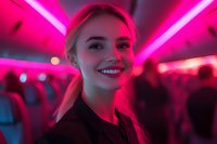 Young blonde woman smiling in vibrant pink neon lighting at night club or party venue, creating atmospheric portrait with glowing ambient illumination and bokeh background.
