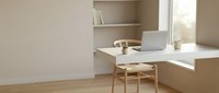 Modern minimalist home office workspace with laptop computer and wooden chair in bright natural light for productivity and remote work.