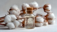 Small glass bottle with cork stopper against backdrop of natural cotton bolls, creating rustic organic spa or cosmetic product scene.
