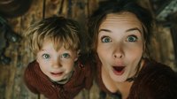 Surprised mother and child making funny shocked faces together, family portrait with wide eyes and open mouths expressing amazement and wonder indoors.