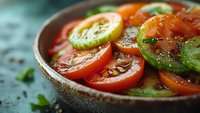 Fresh tomato salad with colorful heirloom varieties, herbs and seasoning in rustic bowl. Healthy Mediterranean cuisine for summer dining and organic cooking.