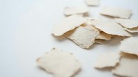 Torn paper pieces scattered on white surface creating abstract texture for creative projects and artistic backgrounds.
