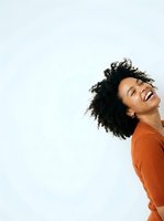 Young woman with dark curly hair and medium skin tone wearing rust-colored top, smiling joyfully against white background. Suitable for lifestyle, wellness, and portrait design projects.