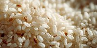 Close-up macro shot of uncooked white rice grains showing detailed texture and natural lighting for cooking and food preparation concepts.