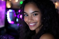 Young African American woman with curly hair and radiant smile against purple and gold bokeh lights background, expressing joy and confidence in nightlife setting.