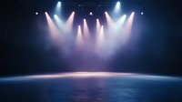 Dramatic stage lighting creates atmospheric scene with multiple spotlights in pink and blue hues casting beams through fog on empty performance space.