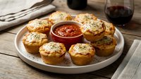 Golden baked potato cups filled with melted cheese and herbs, served with marinara sauce on rustic wooden table for appetizer presentation.