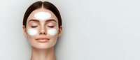 Young woman with closed eyes and white under-eye patches on clean face against light background, demonstrating skincare and beauty treatment routine.