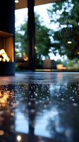 Heavy rain drops falling on wet surface with warm evening lights and bokeh reflections creating atmospheric moody scene through window glass.