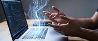 Male programmer's hands creating digital holographic data visualization above laptop with coding interface for modern technology development projects.