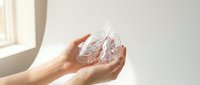 Hands gently holding clear crystal quartz stone in soft natural light near window. Healing crystals, meditation, spiritual wellness concept.