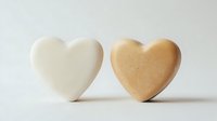 Two heart-shaped soap bars in cream and beige colors on white background for skincare, spa treatments, and romantic wellness concepts.