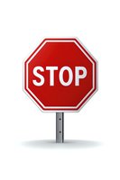Red octagonal stop sign on metal pole isolated on white background. Clean graphic design element for traffic safety and regulatory concepts.