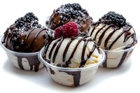 Gourmet ice cream sundaes with chocolate drizzle, fresh berries and toppings in glass bowls isolated on white background for dessert menu design.