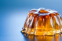 Amber gelatin dessert with glossy surface and translucent texture isolated on blue background, suitable for food photography, culinary websites, recipe blogs, and beverage advertising.