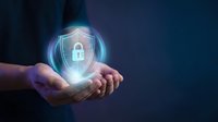 Hands holding glowing digital shield with padlock icon, representing cybersecurity, data protection, and secure network technology for business and digital safety concepts.