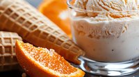 Orange creamy ice cream scoops in glass bowl with waffle cones and fresh citrus fruit slices, sweet cold summer dessert for menu and food design.