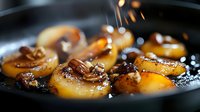 Caramelized banana slices cooking in dark pan with golden syrup drizzling down. Sweet dessert preparation for pancakes, waffles or ice cream topping.