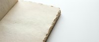 Open blank notebook with textured cream pages and natural binding on clean white surface for writing journaling and creative projects.