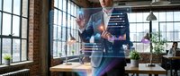 Businessman in blue suit analyzing digital holographic data interface with charts and graphs in modern loft office with large windows and plants.