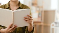 Young woman with light skin tone wearing olive-green shirt holding open blank white book, suitable for education, learning, publishing, and literacy concepts.