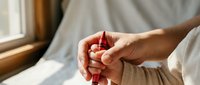 Woman hands holding red heart shape in cupped palms by sunny window. Concept of love, care, charity, donation, health awareness and emotional wellbeing.