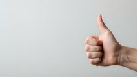 Hand showing thumbs up gesture against neutral background expressing approval, success, and positive feedback for business presentations.