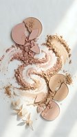 Broken face powder compacts in nude and beige tones scattered on white marble surface with decorative petals for beauty and cosmetics branding.