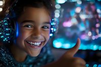 Young African American girl wearing illuminated headphones smiles brightly against blurred blue and purple bokeh background, showing thumbs up gesture in neon lighting.