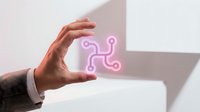 Businessman hand protecting glowing pink network connection icon representing digital connectivity and data protection in modern office environment.