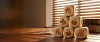 Wooden cubes with business icons stacked on desk near window with warm sunlight creating shadows, representing growth strategy and corporate planning.