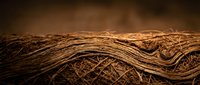 Natural jute rope coils with detailed fiber texture on warm brown background for rustic crafts and nautical projects.