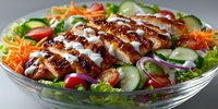 Grilled chicken breast slices with creamy sauce on fresh mixed salad with vegetables. Healthy protein meal for restaurant menu and diet nutrition.