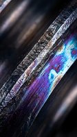 Weathered metal surface with iridescent rainbow oxidation patterns creating colorful corrosion texture on industrial steel beam for abstract backgrounds.