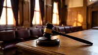 Wooden judge gavel on desk in empty courtroom with warm lighting and traditional architecture for legal proceedings and justice concepts.
