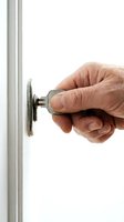 Close-up of mature male hand turning key in door lock against white background. Isolated stock photo for security, home access, real estate, and safety concepts.