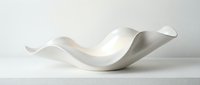 Smooth white ceramic or porcelain sculptural form with flowing, organic curves and waves, isolated on neutral background, suitable for modern interior design, home decor, and artistic projects.