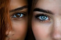 Close-up portrait of two women's eyes - one with deep brown eyes and darker skin, one with bright blue eyes and fair skin, showing diversity and contrast.