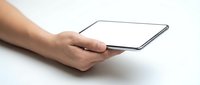 Hand holding modern tablet computer with blank white screen on clean white surface for digital mockup and app presentation purposes.
