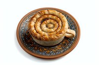 Traditional spiral phyllo pastry pie served on decorative ceramic plate with ethnic pattern, isolated on white background. Mediterranean cuisine.