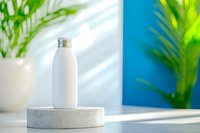 White aluminum bottle on concrete podium with tropical plants and blue wall background, natural sunlight casting soft shadows. Modern minimalist product display.