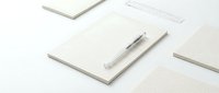 Minimalist office stationery set with lined notebooks, grid paper sheets and silver pen arranged on clean white background for professional workspace design.