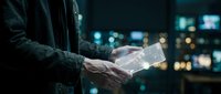 Businessman using transparent tablet device with holographic interface in modern office at night with city lights background for technology presentations.