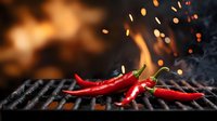 Red hot chili peppers grilling on barbecue grate with fire flames and flying sparks in dark background, dramatic food photography for restaurant menu.