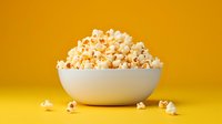 Fresh popcorn in white ceramic bowl against vibrant yellow background with scattered kernels, minimalist food photography composition for snack advertising.
