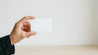 Man's hand holding blank white card against neutral background, suitable for business branding, corporate identity, and marketing presentations.